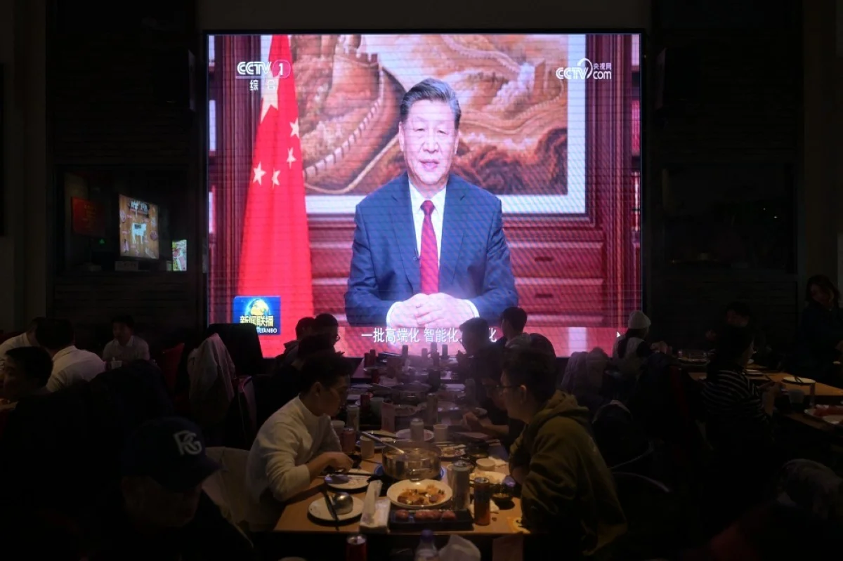 BEIJING, China: People have their dinner at a restaurant as a screen broadcasts China&#039;s President Xi Jinping while delivering his New Year&#039;s speech in Beijing on December 31, 2023. – AFP
