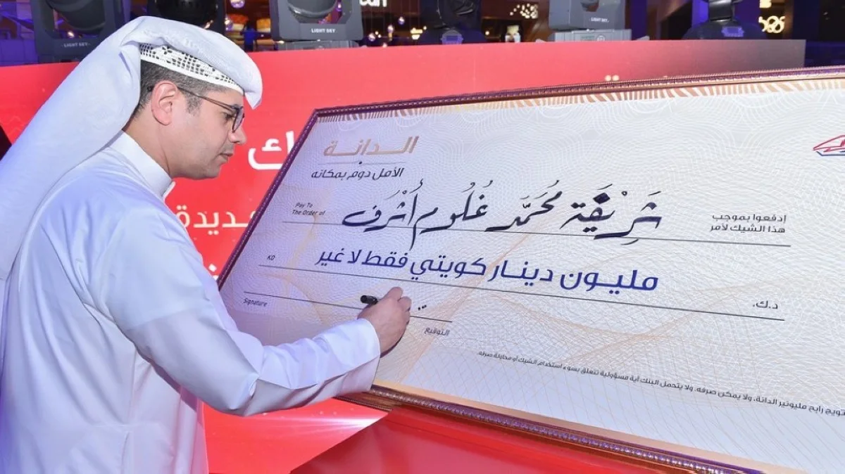 Mohammad Al-Qattan signs the check for the winner of the semi-annual prize in the Al-Danah Millionaire draw.