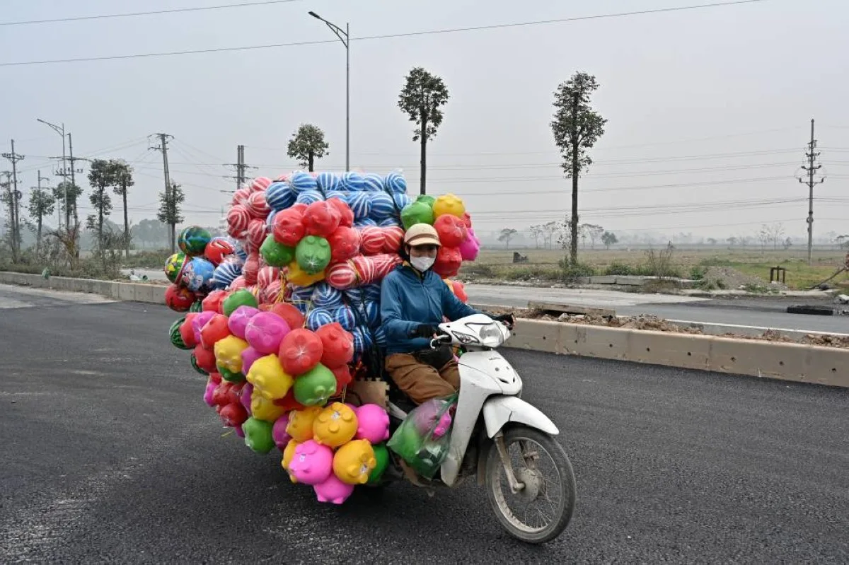 HANOI: A woman rides a motorbike carrying plastic toys on the outskirts of Hanoi.- AFP