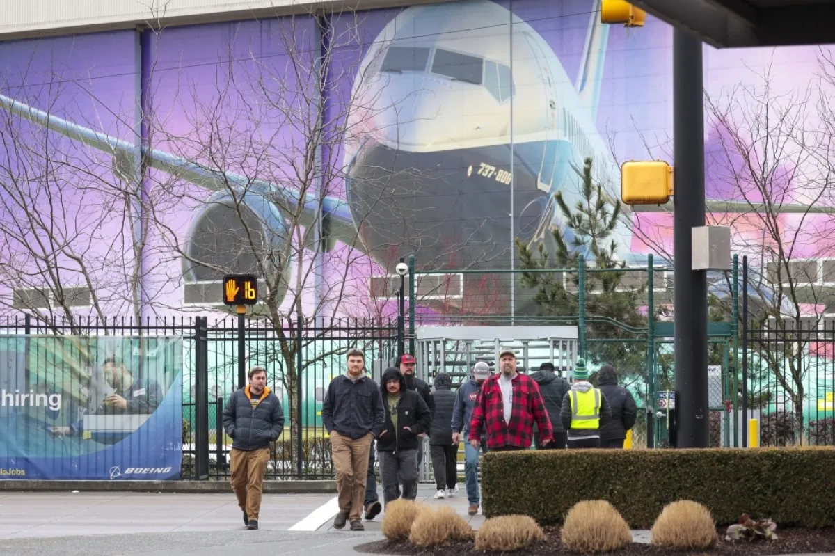 RENTON, United States: Boeing workers are pictured exiting a gate below an image of a Boeing 737-800 aircraft as Boeing&#039;s 737 factory teams hold the first day of a "Quality Stand Down" for the 737 program in Renton, Washington on January 25, 2024.-- AFP

