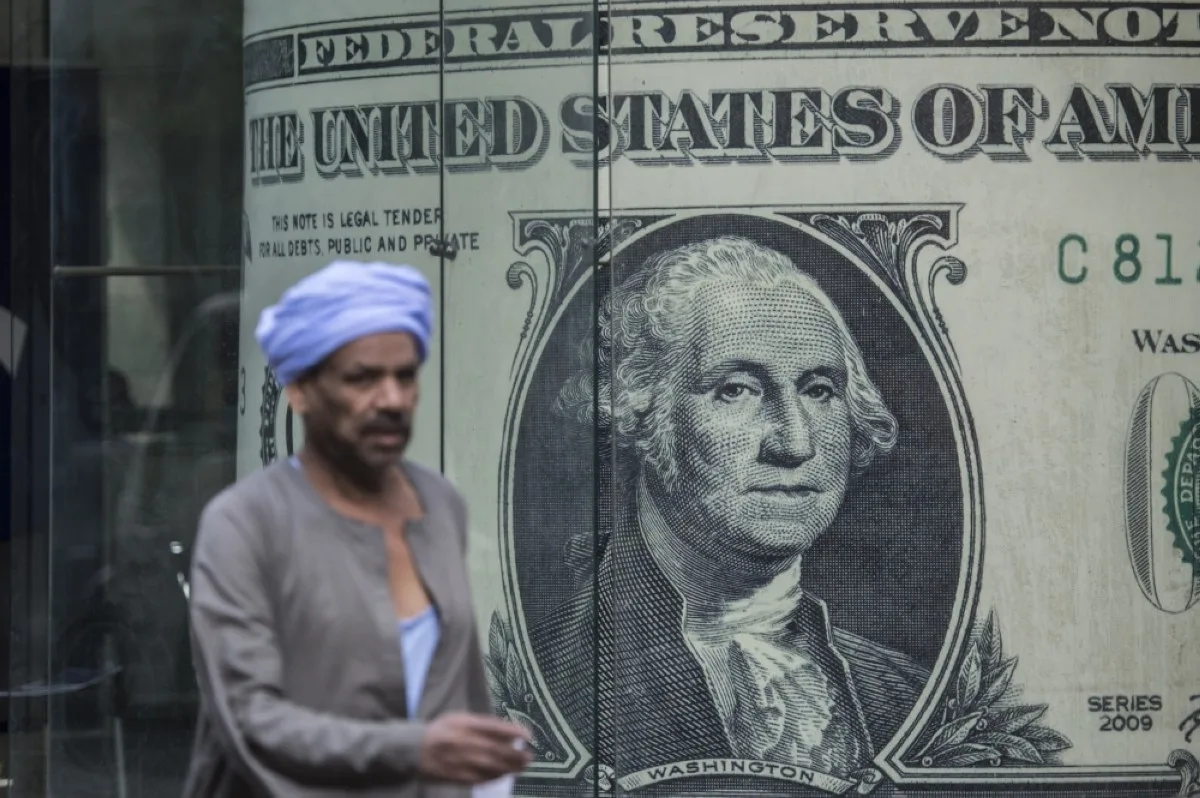 CAIRO: A man walks past a currency exchange shop displaying a giant US dollars banknote in downtown Cairo.輸FP

