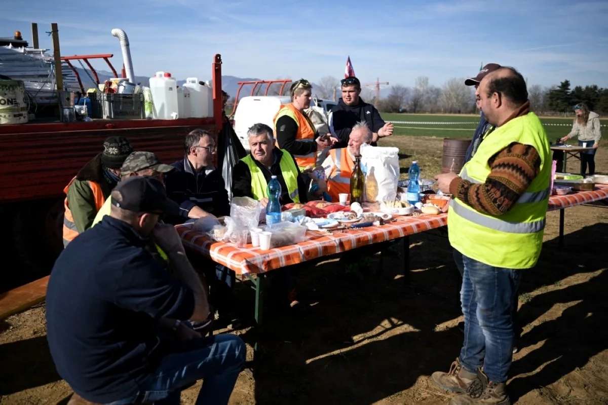 RIVOLI, Italy: Farmers have a lunch and chat after parking their tractors alongside the road during a demonstration near the highway in Rivoli, near Turin, on February 5, 2024. -- AFP