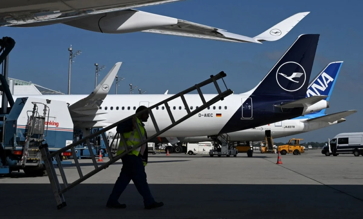 MUNICH: An employee carries a ladder under an Airbus A 350 at the Lufthansa terminal of the Franz-Josef-Strauss-airport in Munich. – AFP

