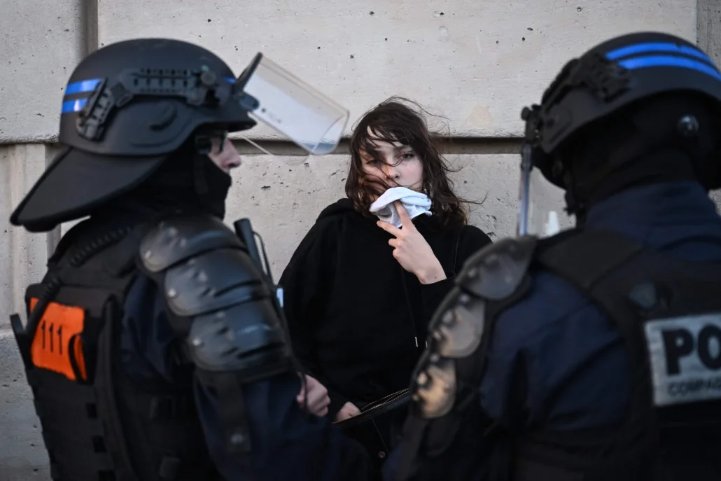 شابة متظاهرة تقف أمام شرطيان 