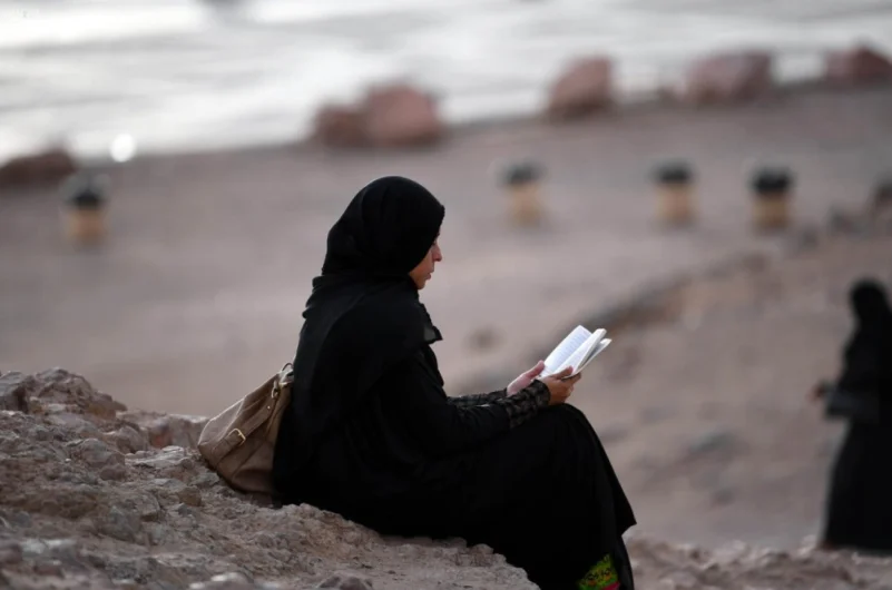 سيدة تقرأ القرآن الكريم بالقرب من مسجد سيد الشهداء بالمدينة المنورة