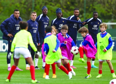 لاعبو منتخب فرنسا يتابعون أطفال يلعبون الكرة قبل بدء التدريب (أ ف ب)