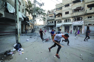 فلسطينيون يفرون من قصف إسرائيلي لمخيم البريج للاجئين (أ ف ب)