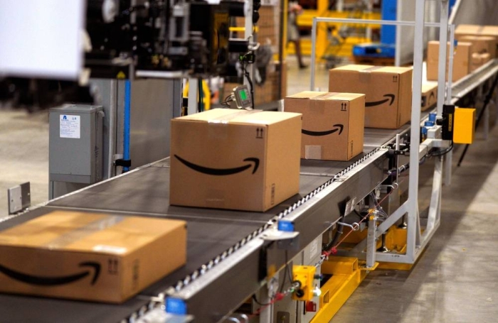 (FILES) In this file photo taken on May 02, 2018, packed orders move down a converyor belt at the Amazon fullfillment center in Aurora, Colorado. - Amazon said Monday, May 13, 2019 it was offering employees $10,000 to quit their jobs and become independent package delivery entrepreneurs for the online retail colossus. An Amazon statement said the latest incentive would also include three months of wages for employees who want to start their own delivery enterprise, and that they would be assured 