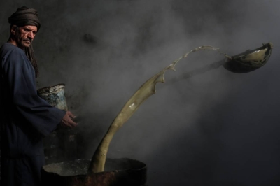 FILED - 01 March 2021, Egypt, Mallawi: A worker stirs sugarcane molasses, known locally as 