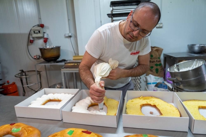 03 January 2023, Spain, Seville: A baker fills a Roscon de Reyes with cream during preparations of the traditional pastry ahead of the day of the Three Kings in Spain. Photo: Francisco J. Olmo/EUROPA PRESS/dpa