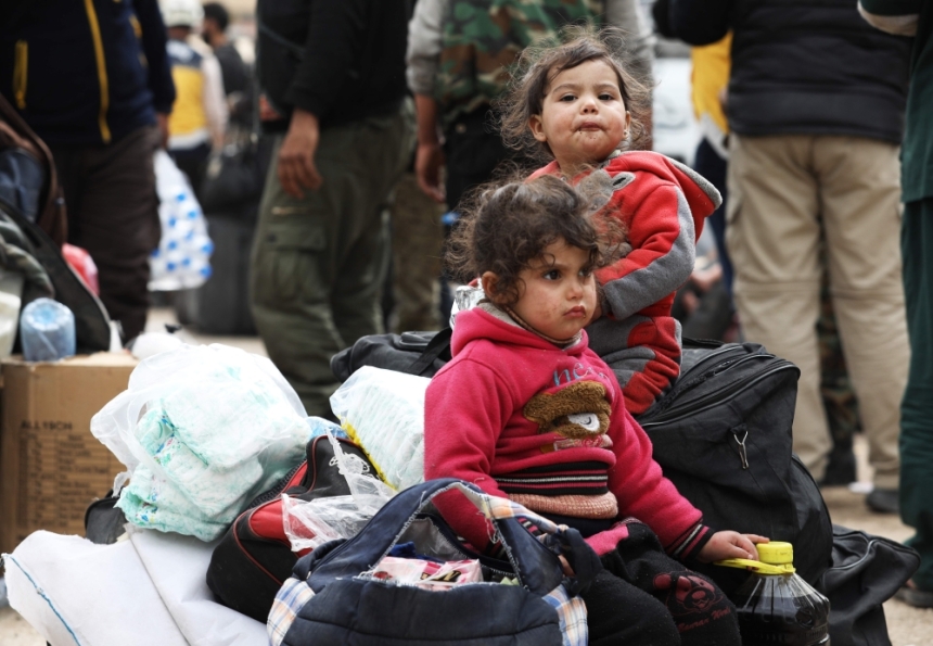 طفلتان تنتظران مع البقية المغادرة من إحدى قرى حما (أ ف ب)