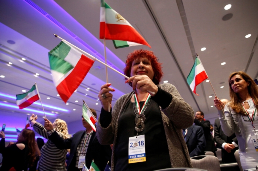 معارضة إيرانية تلوح بعلم بلادها أثناء خطاب جولياني (أ ف ب)