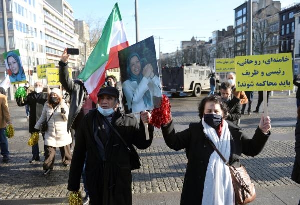 مواطنون إيرانيون يحملون لافتات احتجاج أمام المحكمة البلجيكية (رويترز)