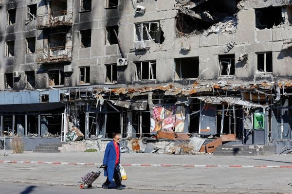 أحد السكان المحليين يمر بجوار مبنى سكني تضرر خلال الصراع الروسي الأوكراني - رويترز