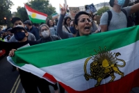 إيرانية في لندن تحمل علم المجلس الوطني للمقاومة وتهتف بسقوط النظام (رويترز)