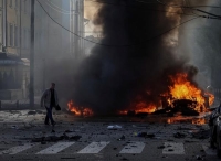سائق يسير بالقرب من سيارته المحترقة بعد الضربة العسكرية الروسية على كييف - رويترز