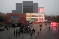 FILE PHOTO: Customers line up outside store of the Uniqlo fast fashion retailer to attend its opening in the Sanlitun shopping district on a polluted day in Beijing, China, November 6, 2021. REUTERS/Thomas Peter/File Photo