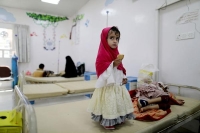فتاة تقف على سرير أختها التي تتلقى علاجًا كيميائيًا بمستشفى في العاصمة المختطفة صنعاء - رويترز