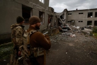 جنود أوكرانيون يقفون بجوار مبنى مدرسة دمرته غارة جوية روسية في منطقة ميكولايف- رويترز