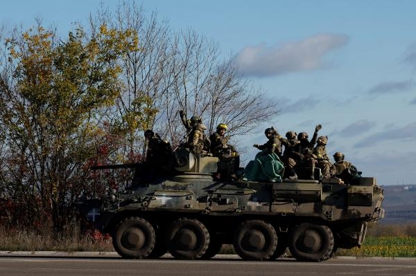أفراد من الجيش الأوكراني يلوحون وهم يقودون سياراتهم على طريق رئيسي - رويترز