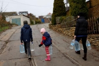 أوكرانيون يحملون قوارير مياه في خيرسون عقب انسحاب الروس من المدينة - رويترز