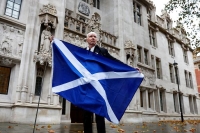 ناشط مؤيد لاستقلال اسكتلندا يقف بعلم اسكتلندي خارج المحكمة العليا البريطانية - رويترز