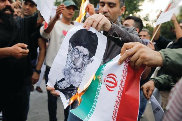 متظاهرون يحرقون صورة خامنئي والعلم الإيراني أمام سفارة النظام في أثينا - رويترز
