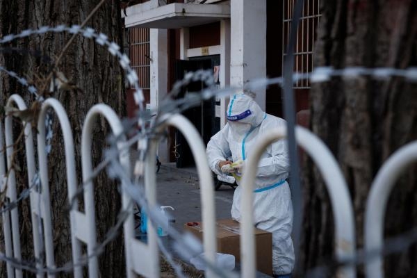 عامل يرتدي بدلة واقية في مجمع سكني مغلق جزئيًا بالصين - رويترز