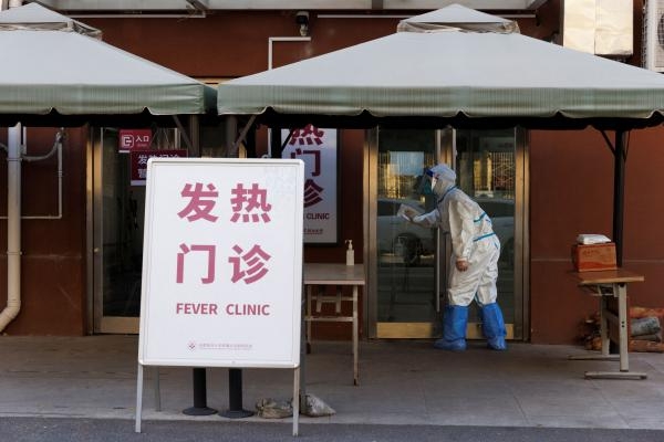 عامل صحي يرتدي بدلة واقية يمسح باب عيادة الحمى في مستشفى بالصين - رويترز