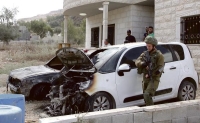 جندي للاحتلال قرب سيارتين أحرقهما المستوطنون - أ ف ب