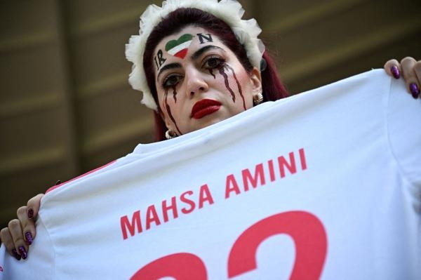 مشجعة في المونديال تمسك بقميص يحمل اسم الشابة الكردية مهسا أميني - رويترز