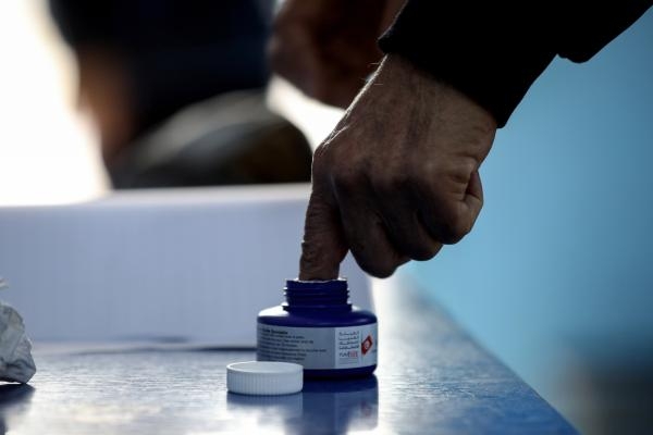رجل تونسي يغمس إصبعه بالحبر بعد التصويت في مركز اقتراع - د ب أ