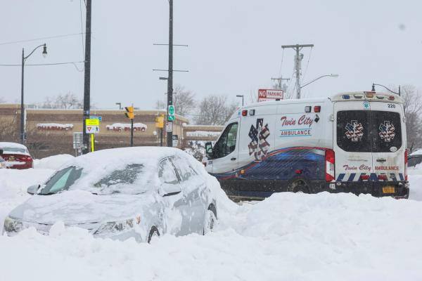 سيارة إسعاف تمر بسيارة مهجورة مغطاة بالثلوج خلال العاصفة الشتوية في منطقة بوفالو- رويترز