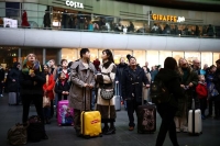 بريطانيون ينتظرون تحت شاشات المعلومات التي تعرض أوقات القطارات في محطة كينجز كروس- رويترز