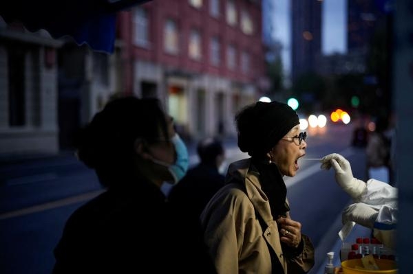 امرأة تخضع لفحص كورونا في موقع اختبار بعد تفشي المرض في شنغهاي - رويترز