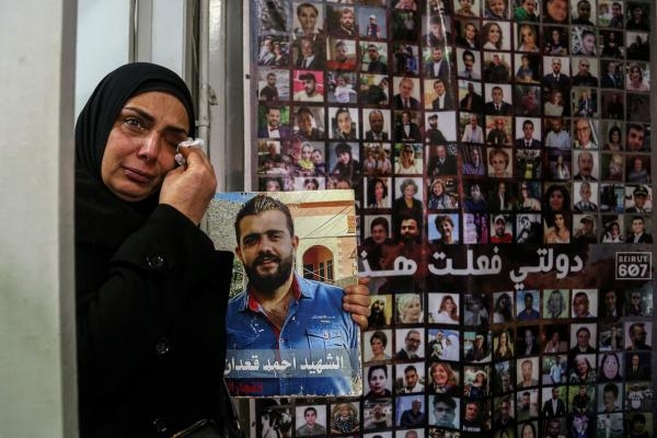 لبنانية تحمل صورة ابنها الذي راح ضحية بانفجار المرفأ في 2020 - د ب أ