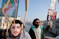 متظاهر يرتدي قناعا لأحد ضحايا أحكام الإعدام خلال الاحتجاجات الإيرانية - رويترز