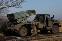 جندي أوكراني يركض بجوار نظام إطلاق صواريخ متعدد - رويترز