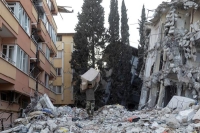 رجل يخرج أريكة من مبنى سكني دمره الزلزال بمدينة هاتاي في تركيا - رويترز