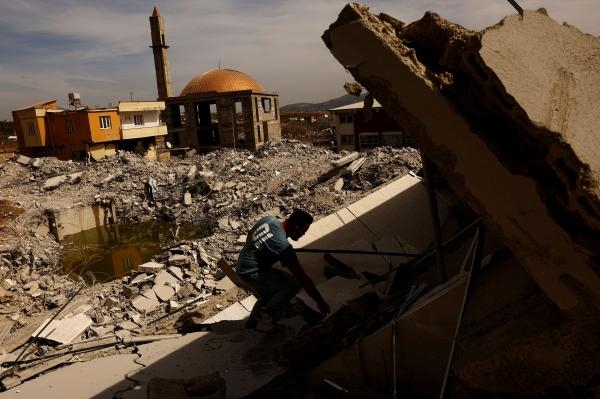 رجل يساعد في إنقاذ الممتلكات من منزل منهار عقب الزلزال في تركيا - رويترز