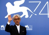 الموسيقي والملحن الياباني ريويتشي ساكاموتو يلوح في مهرجان البندقية السينمائي الرابع والسبعين في إيطاليا سبتمبر 2017 - رويترز