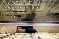 مندوب مبيعات يقف مع مجوهرات من الذهب في متجر بيع المجوهرات بالتجزئة في الصين - رويترز