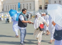 أحد الكشافة يرشد حاجة خلال سيرها في مكة المكرمة 