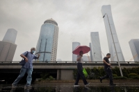 مواطنون يسيرون تحت المطر في الصين - رويترز 