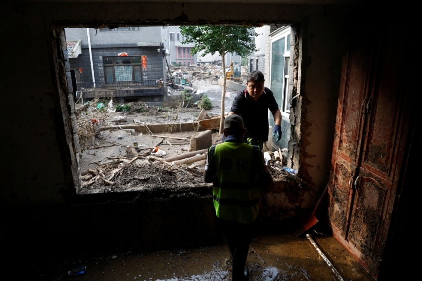 عامل ينقل أشياء عثر عليها في الأنقاض منزله دمرته الفيضانات - رويترز