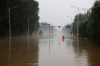 رجل يشق طريقه عبر طريق غمرته المياه بعد هطول الأمطار والفيضانات في الصين - رويترز