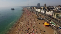 رواد الشاطئ يبردون أجسادهم في الماء أثناء الطقس الحار في بريطانيا- رويترز