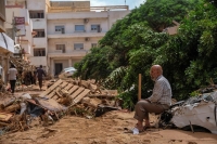 رجل يجلس على سيارة مدمرة بعد عاصفة قوية وأمطار غزيرة ضربت ليبيا- رويترز