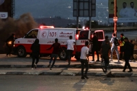  فلسطينيون يركضون إلى سيارة إسعاف خلال اشتباكات مع قوات الاحتلال - د ب أ