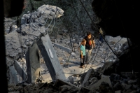 أطفال يقفون قرب ركام منزلهم بغزة - رويترز